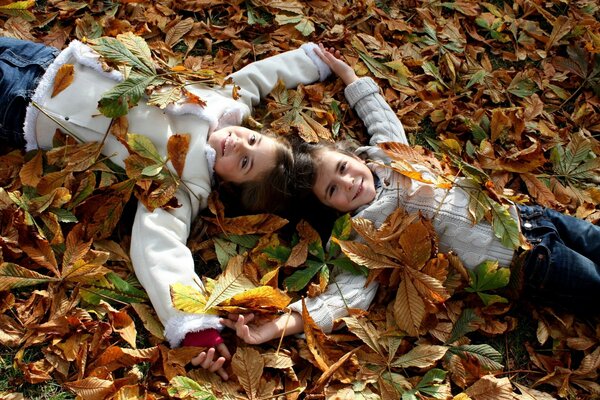 Los niños felices yacen en las hojas de otoño