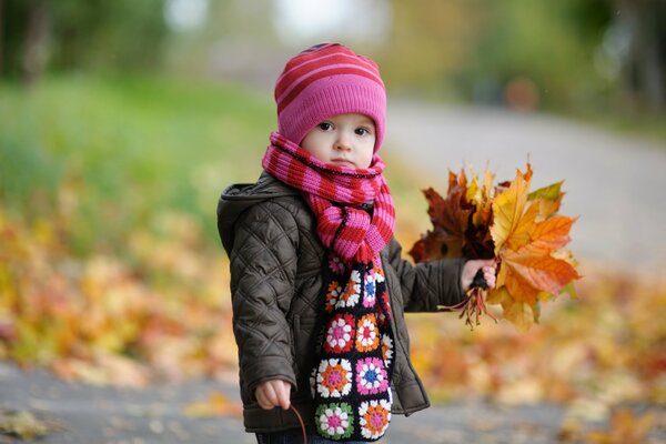 Bebé con un ramo de hojas de otoño