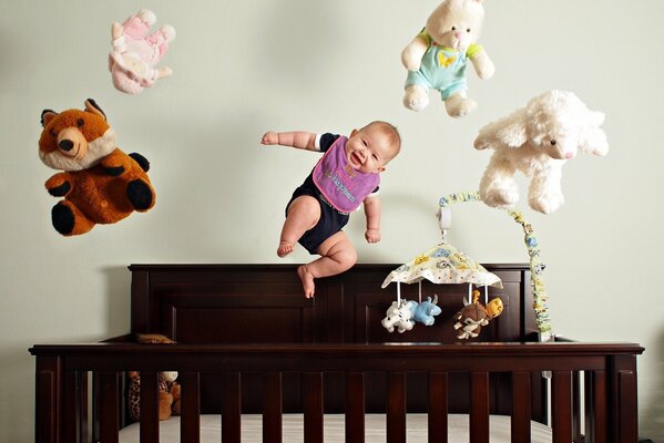 Bebé saltando con juguetes en la cuna