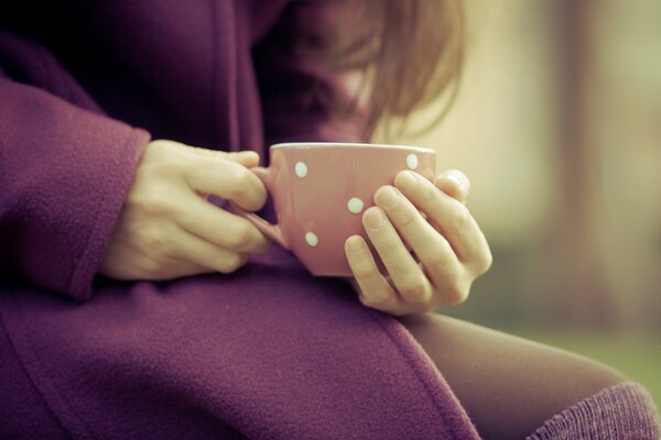 Ragazza scalda le dita su una tazza di caldo Macro