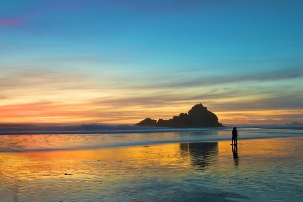 At sunset, a couple in love walks on the beach