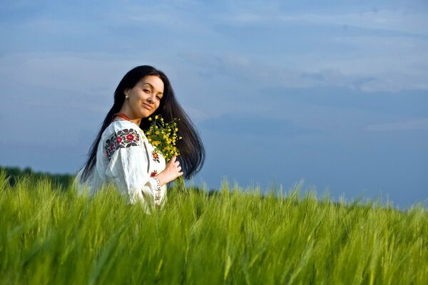 Jeune fille assise dans l herbe avec des fleurs à la main