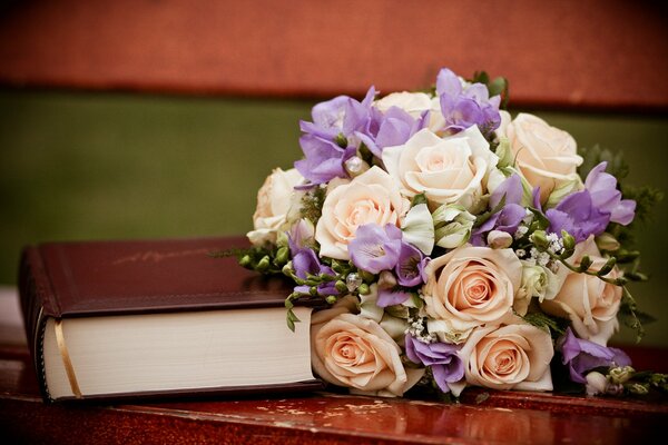 Ein Buch und ein wunderschöner Blumenstrauß auf der Bank