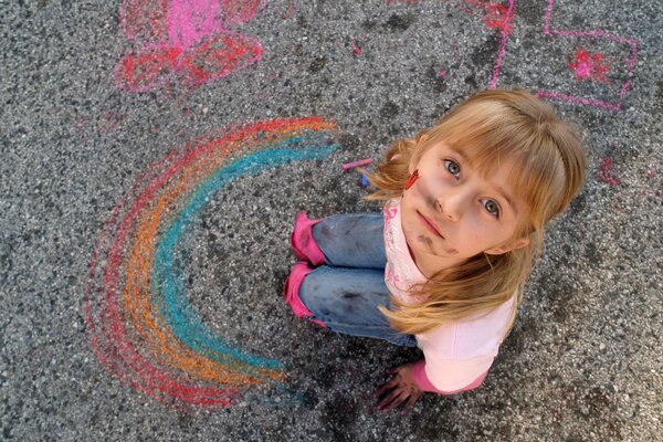 Das verschmutzte Mädchen malte einen Regenbogen auf den Asphalt