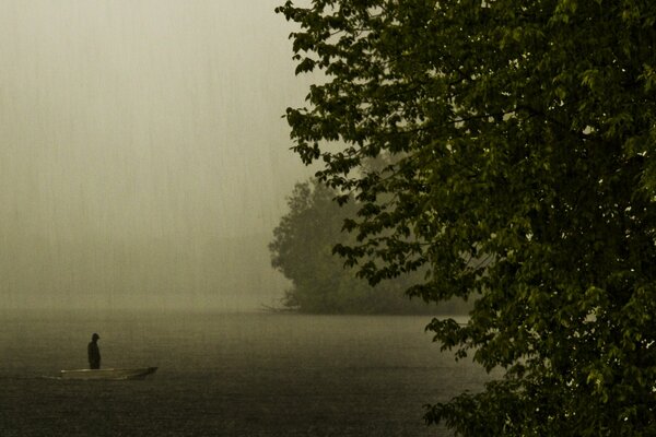 Silhouette dans un bateau sur un lac dans une soirée pluvieuse