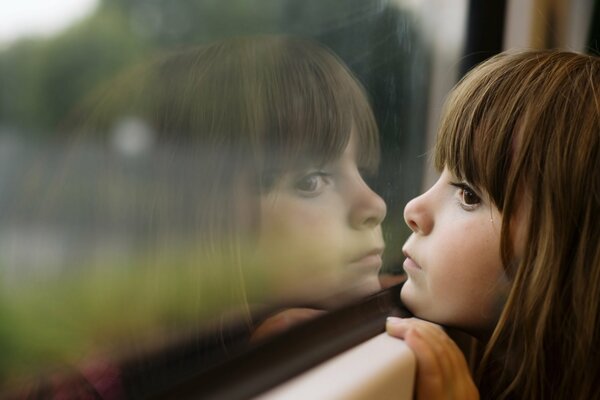 Petite fille de réflexion dans la fenêtre