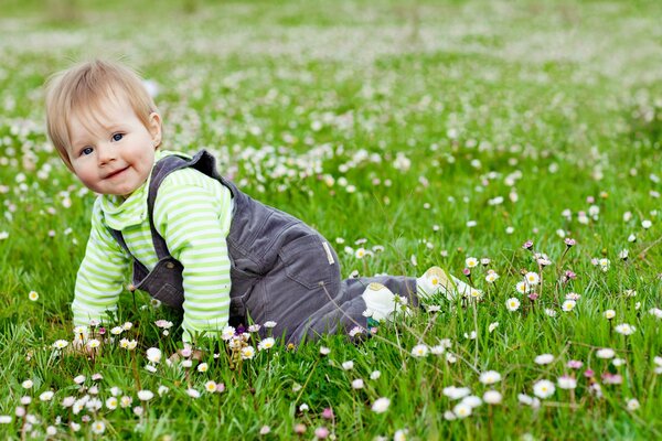 Bebé feliz sentado en la hierba con flores
