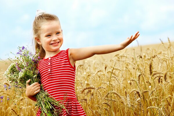 Niedliche kleine Mädchen mit Blumen im Weizenfeld