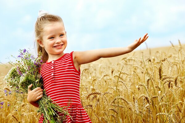 Mignonne petite fille avec des fleurs dans le champ de blé