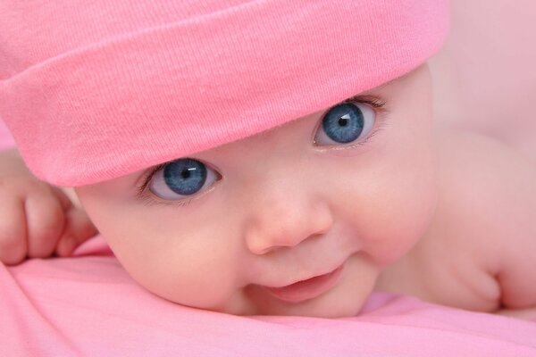 A beautiful baby with blue eyes in a pink hat