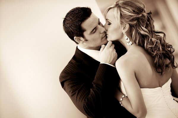Un homme en costume et une femme en robe blanche s embrassent