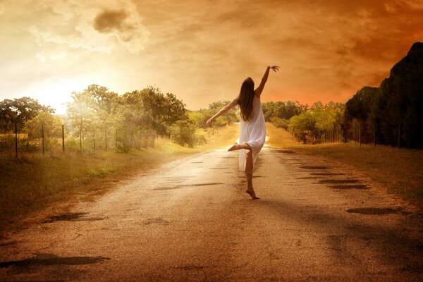 A girl dancing on the road against the background of nature