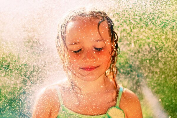 A girl with her eyes closed stands in the rain