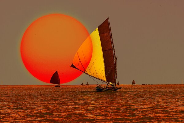 Ungewöhnlicher roter Sonnenuntergang am Meer und Segel