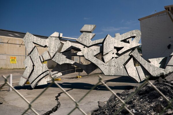 Three-dimensional graffiti made of metal behind a mesh fence