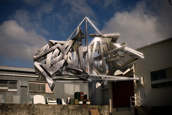 Three-dimensional graffiti made of metal on the background of the building