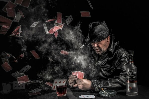 A brutal man plays cards and drinks