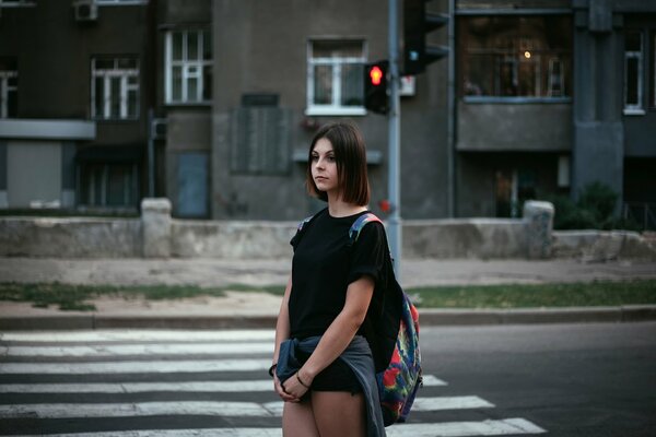 A lonely girl in the city at a traffic light