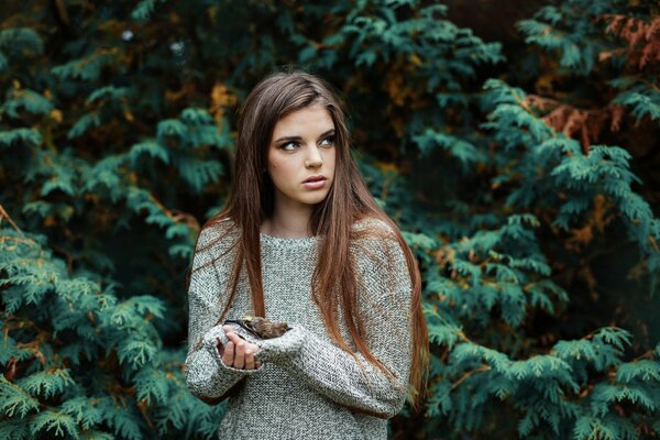 Девушка в свитере с мертвой птицей в руках