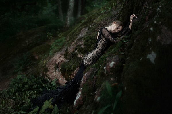 La composition avec la nature. La jeune fille dans une robe noire dans la forêt
