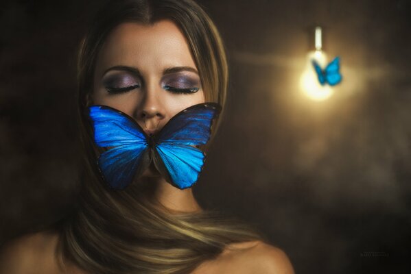 La jeune fille pose avec un papillon sur un fond sombre