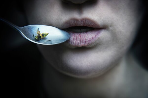 Labbra femminili e cucchiaio con ape