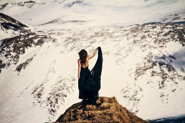 Ragazza in abito nero nelle montagne innevate