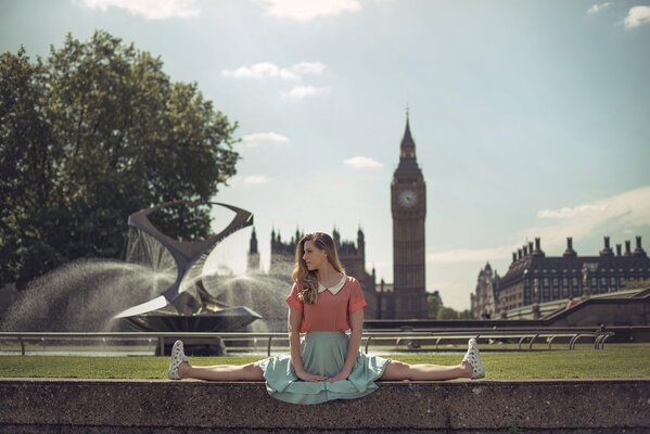 Девушка, сидящая на шпагате на фоне видов Лондона