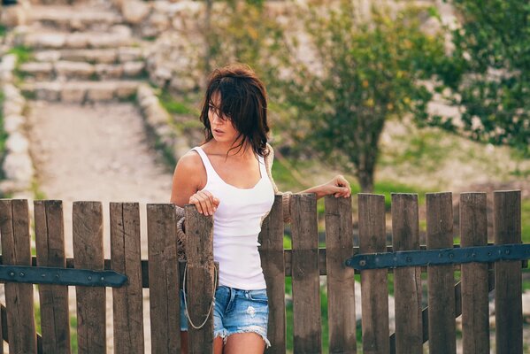 The girl is standing near the gate in the village