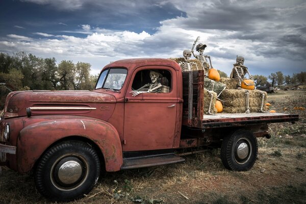 Skeletons on Halloween ride in a truck with pumpkins and hay