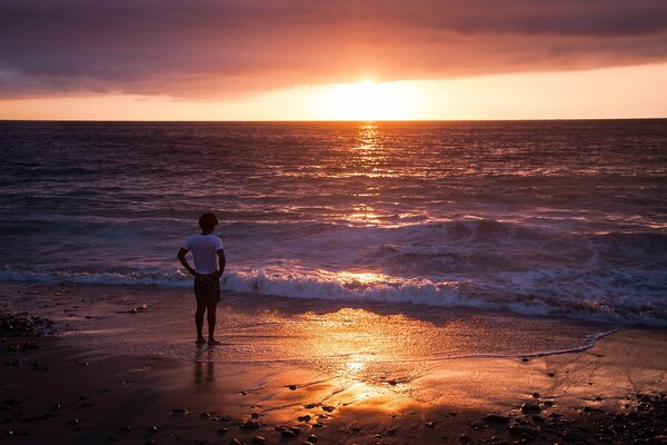 L homme en regardant le coucher de soleil au bord de la mer