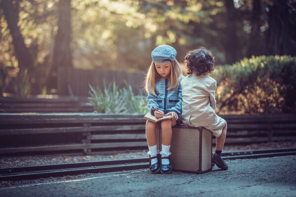 Mignons les enfants sont assis sur la valise