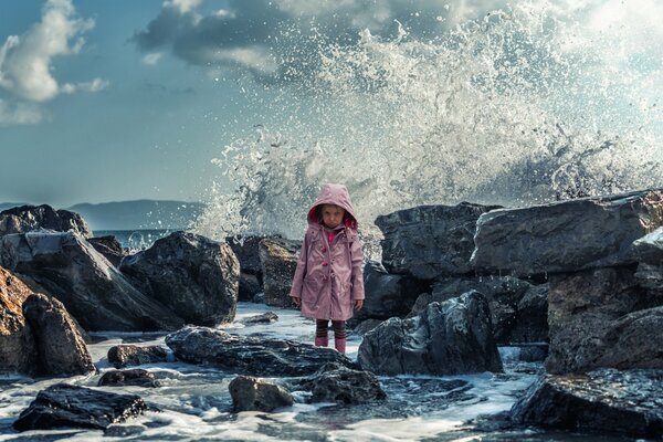 A girl standing in the water on the rocks