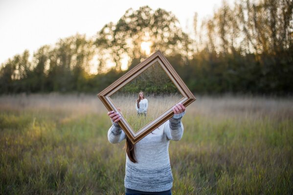 Foto di una ragazza con uno specchio. Illusione