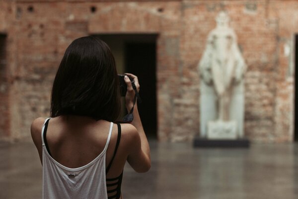 A girl with a short haircut photographs a statue