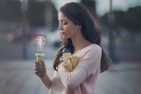 Bella ragazza che tiene una lampadina con il potere del pensiero