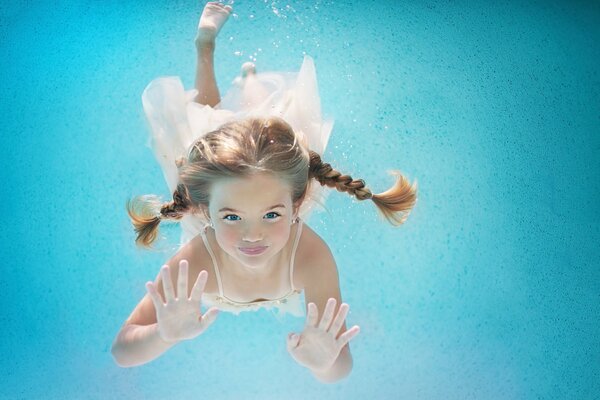 A girl with pigtails swims underwater. Happy summer