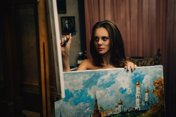 A girl artist draws and holds a picture in her hand