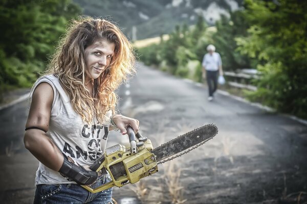 Chica en las manos con una motosierra en las montañas