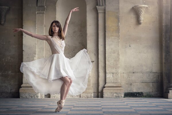 Schöne Ballerina im weißen Kleid in einem alten Gebäude