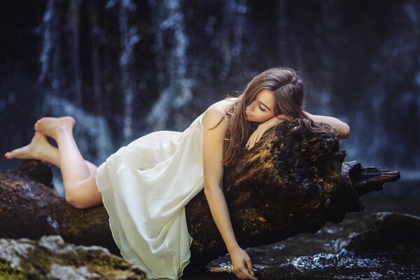 Das Mädchen träumt im Wald auf einem liegenden Baum. Ihre Beine ruhen sich nach einem langen Spaziergang aus