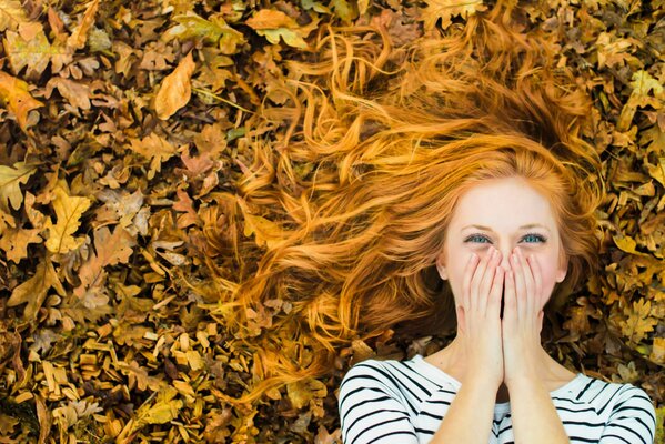 Chica pelirroja en follaje de otoño