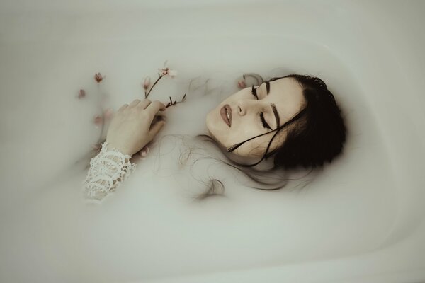 Das Mädchen liegt in der Badewanne, umgeben von Blumen