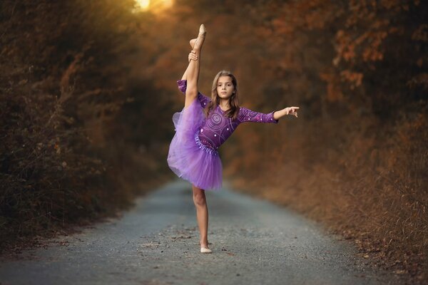 Ragazza in tutu viola che balla nella foresta