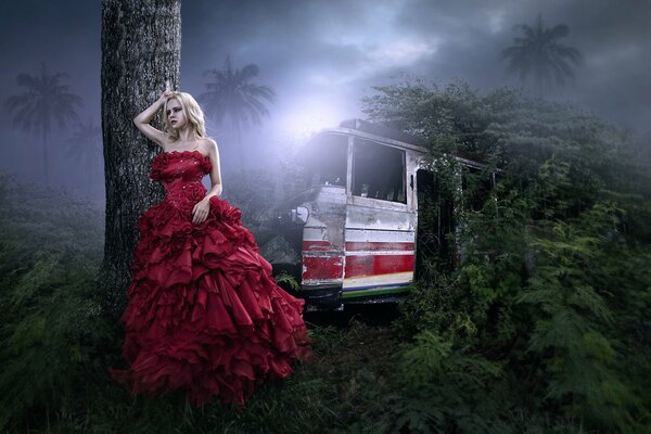 La jeune fille dans une robe rouge dans l obscurité de la jungle