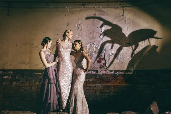 Тень паука на стене за спинами трех девушек