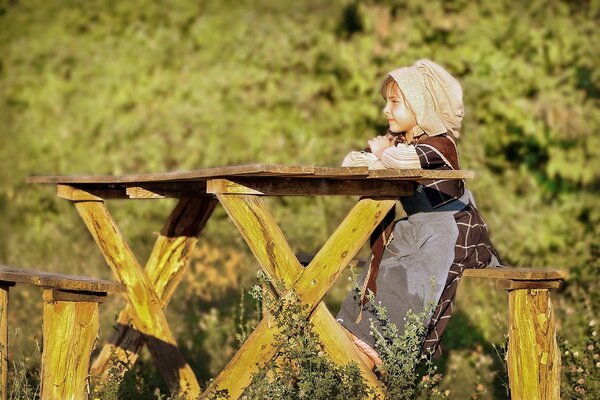 The girl is sitting at the table on a bench