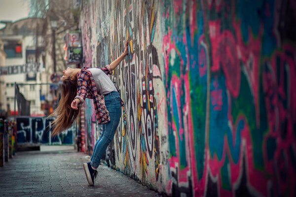 A girl in the city near a beautiful graffiti