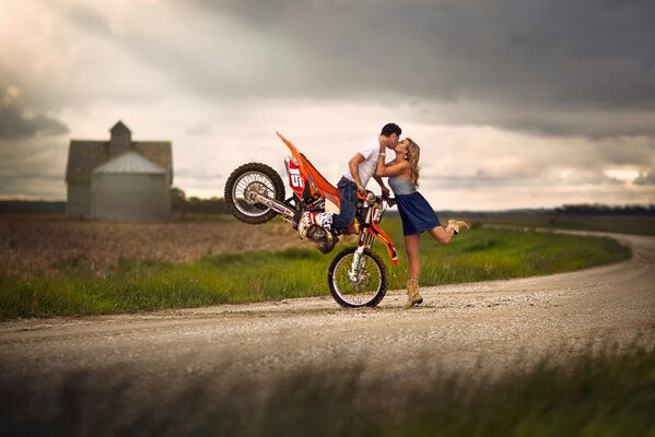 A guy sitting on a motorcycle kisses a girl