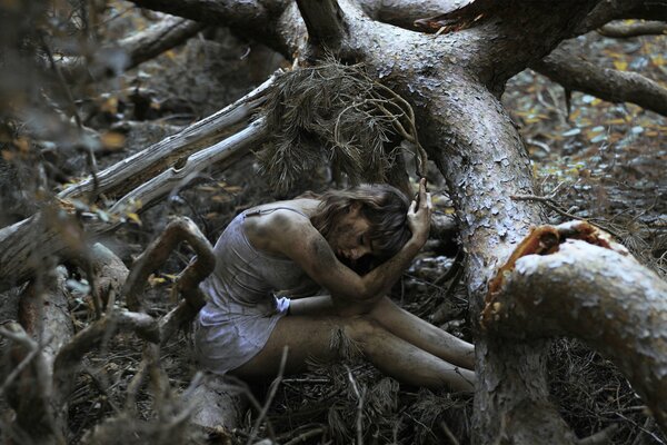 A beautiful girl is sitting in a dirty forest, surrounded by trees